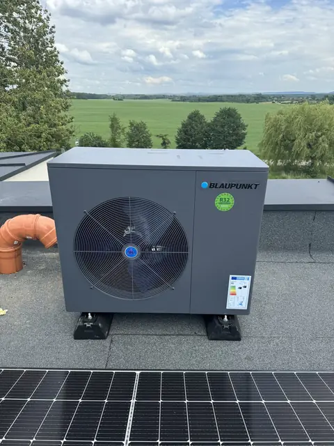 Heat pump on a roof next to a PV system